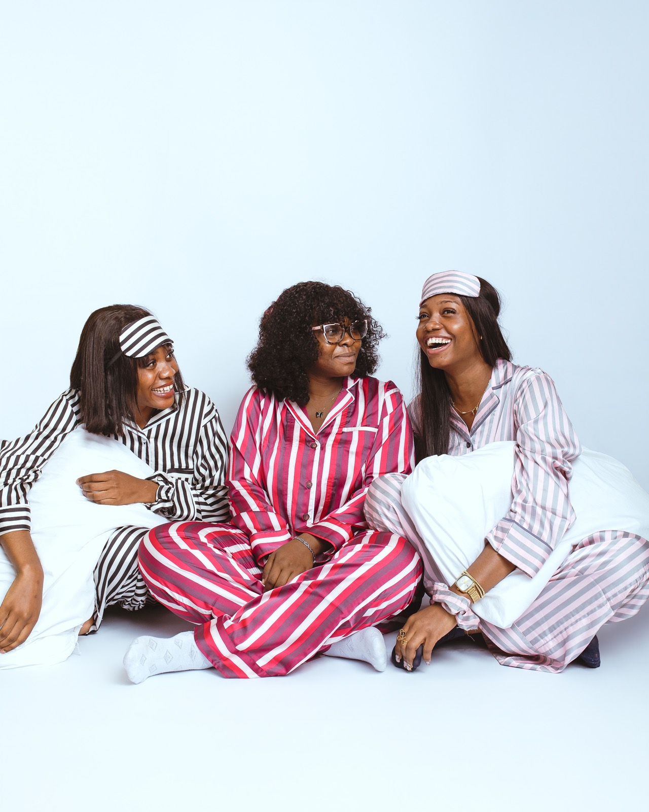 Three women in striped pajama sets laughing together